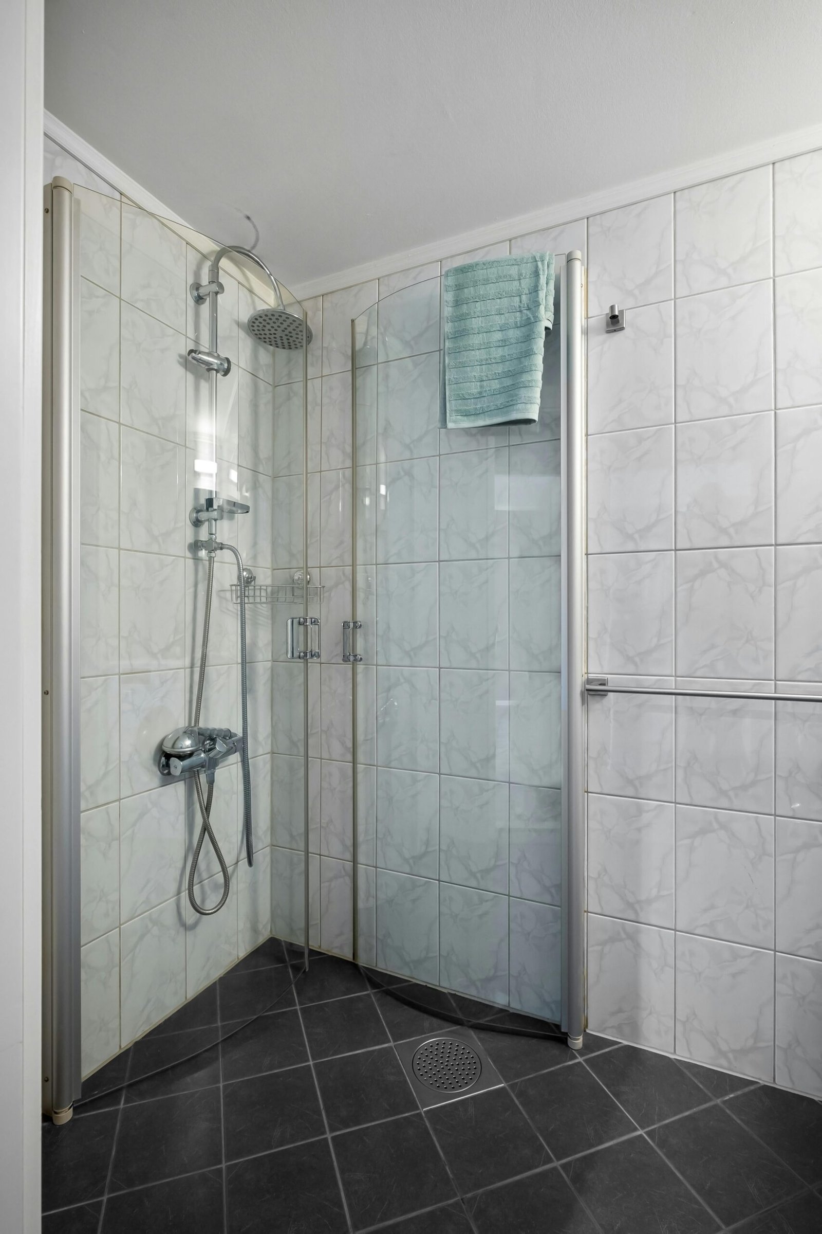Sleek glass shower enclosure in a contemporary bathroom featuring white tiles and modern fixtures.